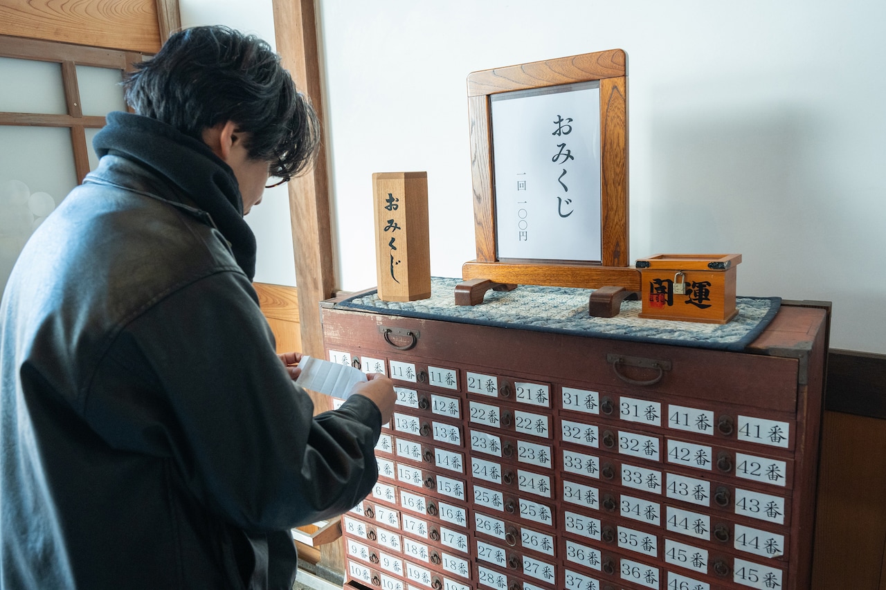 おみくじに書かれたお告げを確認する後藤正文。
