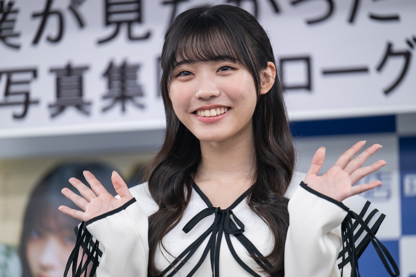 笑顔で手を振る金澤亜美。