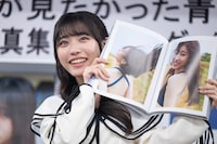 写真集からひょっこり顔を覗かせる金澤亜美。