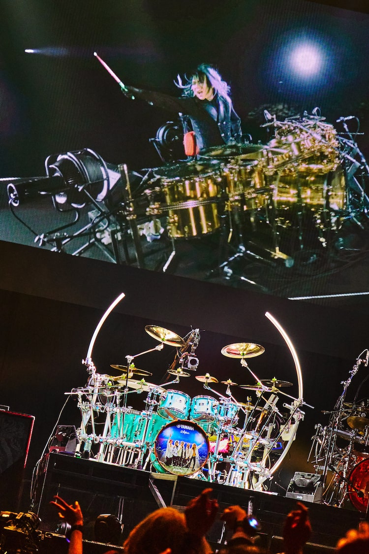 ありし日の真矢（Dr）のパフォーマンス映像と彼のドラムセット。