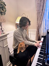 プリンちゃんを膝に乗せながらピアノを弾く角野隼斗。