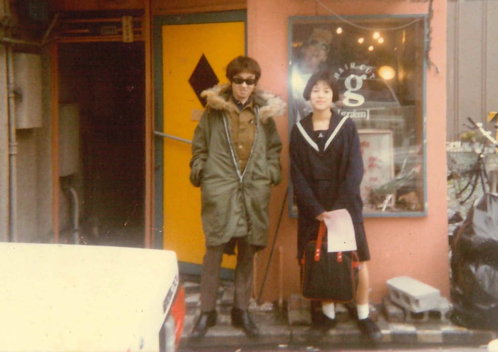 高校時代の原田。グラムの店先にて小出水氏と。よく見ると原田の後ろにパックマンが写っている。