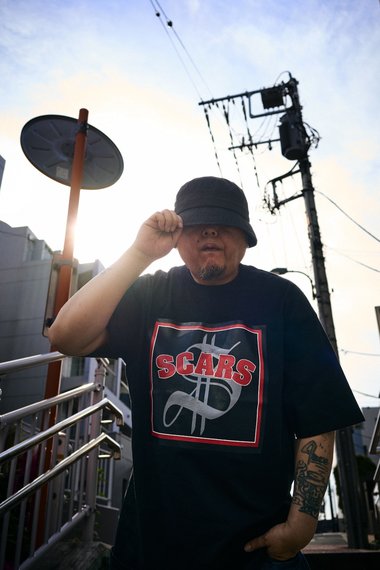 SCARS「THE ALBUM」のジャケットデザインを用いたTシャツを着用したBES。