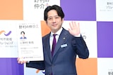 “に野村和也”の巨大名刺を持って手を振る二宮和也。