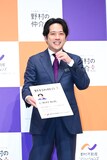 “に野村和也”の巨大名刺を差し出したあと、照れ笑いする二宮和也。