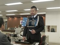 CMの一風景。上司の話に困り顔のケンドーコバヤシが「ホールズ®」を取り出し、気分をスッキリさせるために口にほうり込むと、胸元が開き……。