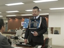 CMの一風景。上司の話に困り顔のケンドーコバヤシが「ホールズ®」を取り出し、気分をスッキリさせるために口にほうり込むと、胸元が開き……。