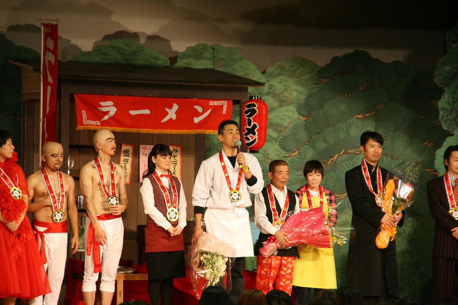 演者全員に松南高校から校章と今回の吉本新喜劇50周年にかけて5円玉10枚がデザインされた手作りの首飾りが贈呈された。(c)吉本興業