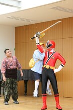 身長差を顧みずなんとか剣をシンケンレッドから取ろうとするめだか。(c)吉本興業