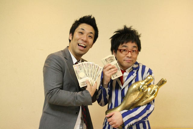 賞金の1000万円を手にしたパンクブーブー。会見で「M-1グランプリ2010」に挑戦するかを問われると、2人とも「1年後の予想がつかない」と、日々の仕事に精一杯の様子。(c)吉本興業