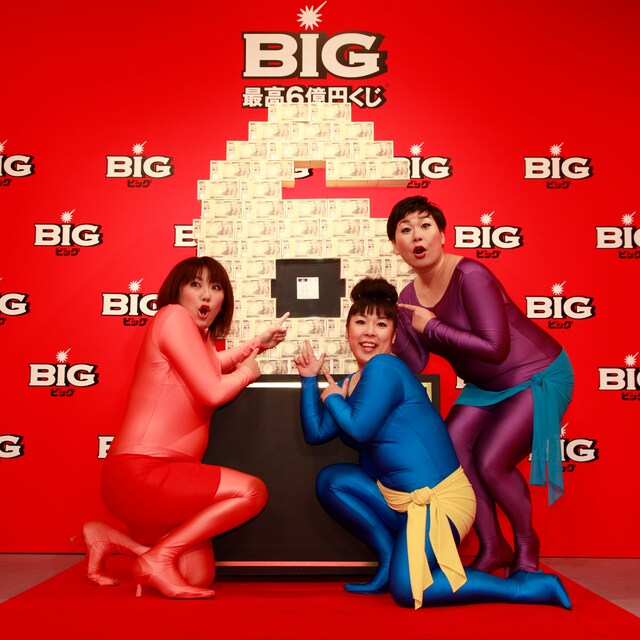 ステージ上に置かれた6億円分のお札のレプリカにすり寄る森三中。過去に6億円に当選したチケットも置かれ、縁起のよいオブジェとなっている。