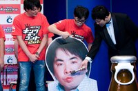 パネルの塚地にマイクを向ける司会のあべこうじ。