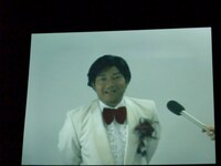 ムード歌謡歌手の丸取柄フリオは、母親の故郷である中国に滞在していたところ、友人のチンさんのミスで日本に帰るチケットが取れず会見を欠席。CM撮影の日には、自身が経営するスナック2号店の仕込みで撮影終了後すぐに飛び出すなど多忙な様子だ。