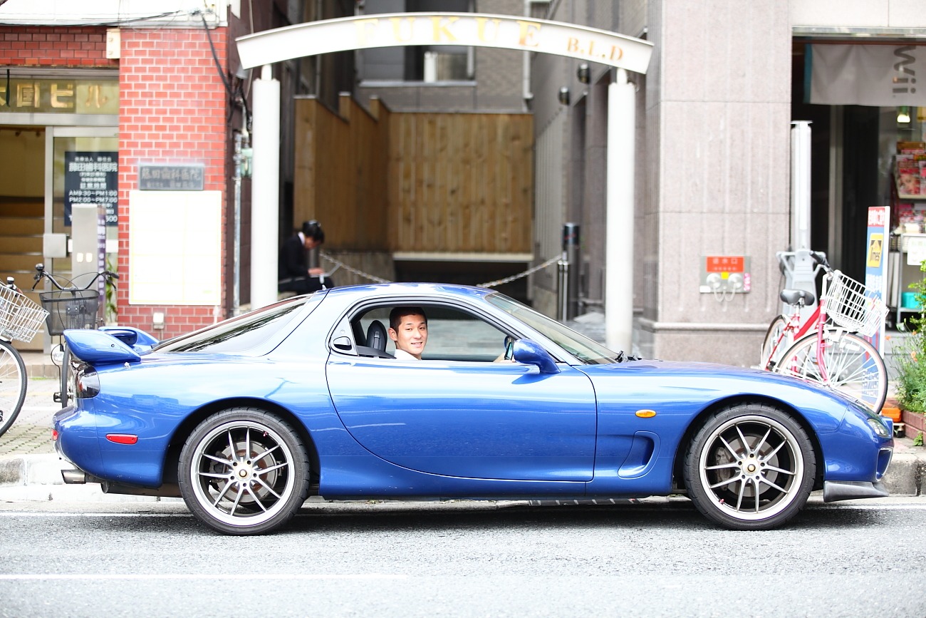 「笑い飯全一冊」に掲載予定の写真。愛車から顔をのぞかせる哲夫。(c)吉本興業