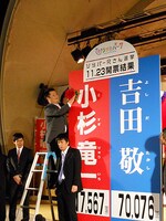 当選記念の花を付ける小杉。それに対し終始不機嫌な吉田。