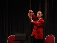 手品師の阪野登。この日は紙幣を使ったマジックを披露した。「カンボジアではウケるんですが、イラクではウケないんです」と、同じ芸でも国よって反応が違うことを明かした。