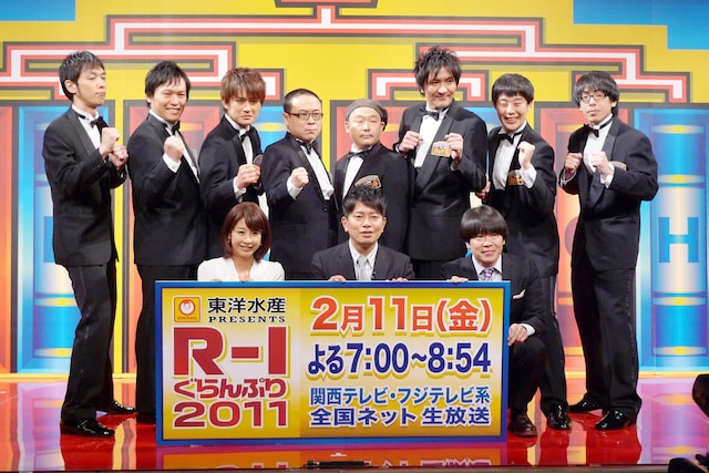 「R-1ぐらんぷり2011」の決勝進出者発表会見に出席したAMEMIYA、佐久間一行、スリムクラブ真栄田、バッファロー吾郎・木村、COWCOW山田よし、キャプテン渡辺、ナオユキ、ヒューマン中村の8名と司会の雨上がり決死隊（写真前列右）、加藤綾子（フジテレビアナウンサー、写真前列左）。