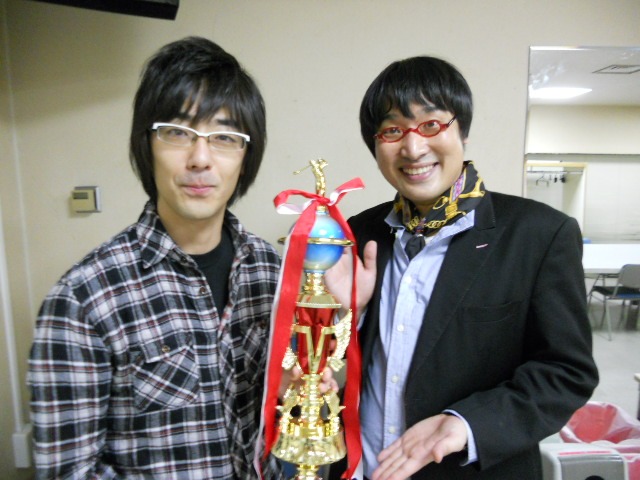 「言語遊戯王8」で優勝した東京03豊本とMCの南海キャンディーズ山里。試合中山里は「豊本さんは大きな声を出さない人というイメージ」と語り、その言葉通り豊本は終始冷静な試合運びで勝利を決めた。