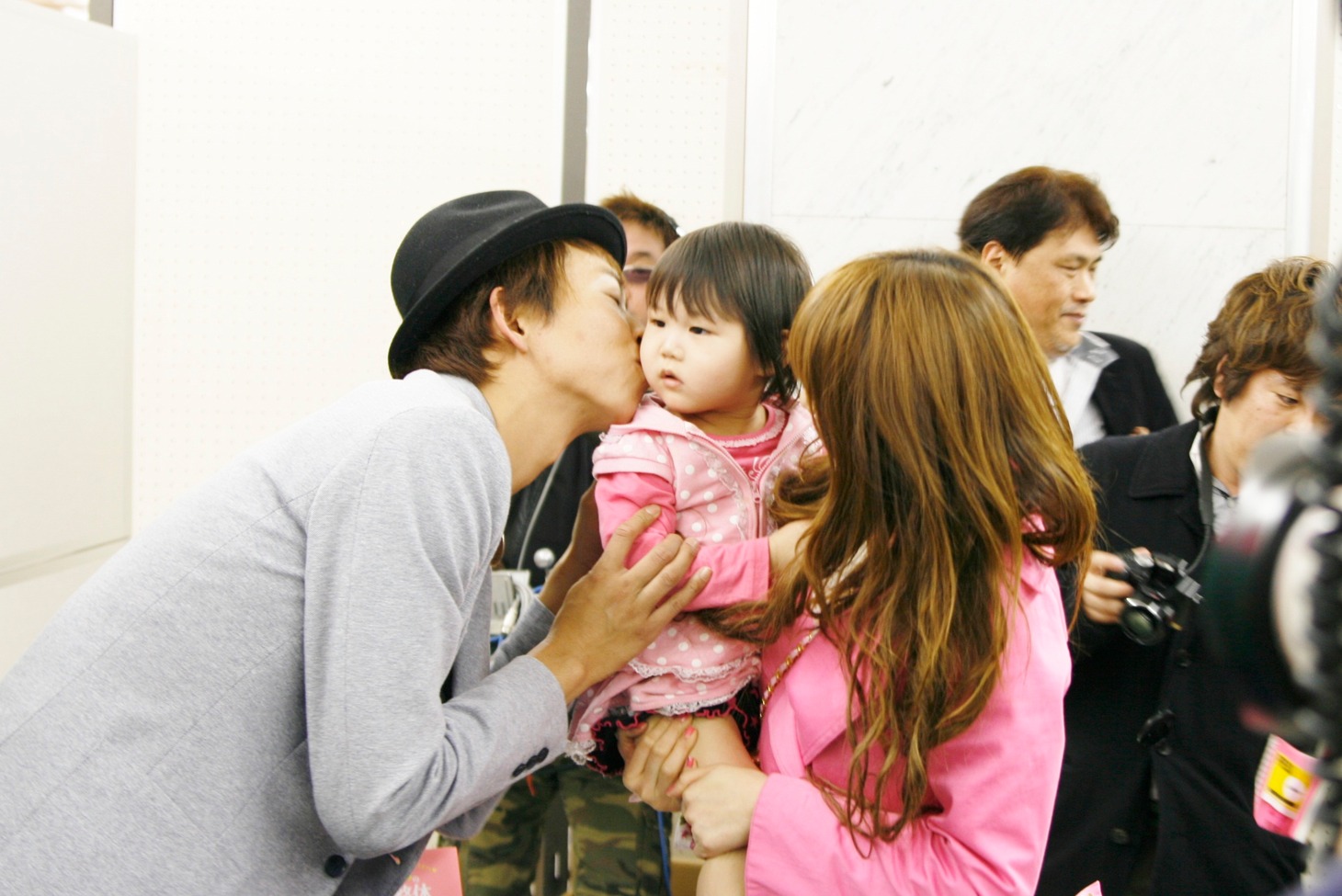 ファンとの握手会で幼児の頬にキスをする楽しんご。