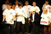 木本と沖縄旅行に行った際に買ったという思い出の詰まったループタイを出品したビーグル38能勢。この後加藤の元気いっぱいなキャラも出現。(c)松竹芸能