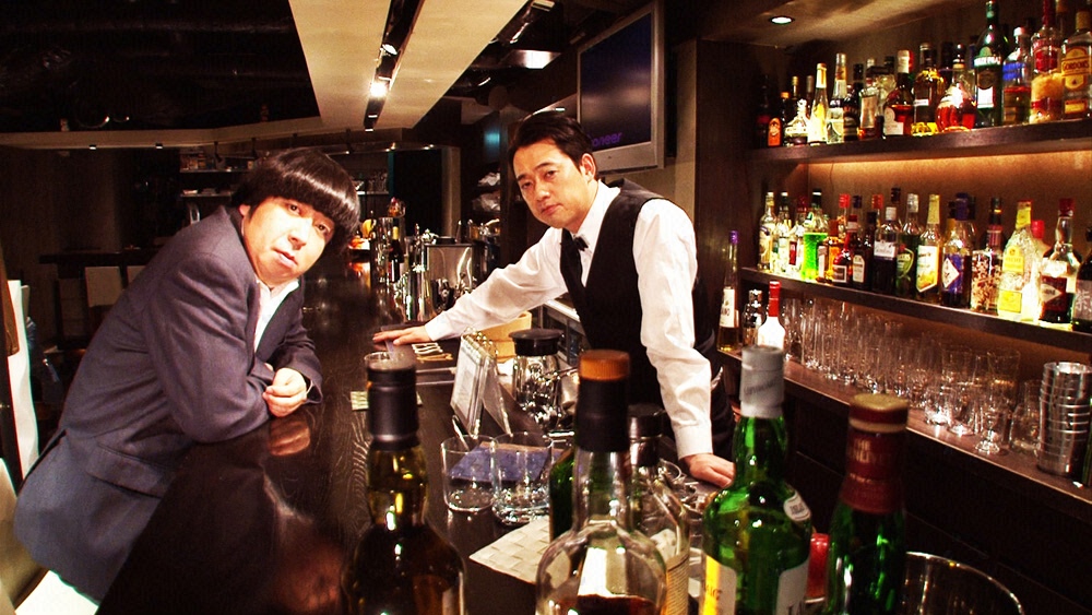 Barのマスター役で登場する設楽（右）と、冴えないサラリーマン役の日村（左）。(c)CSフジテレビONE