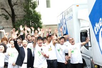 引っ越しの荷物を載せて各地へ出発するトラックを見送る一同。