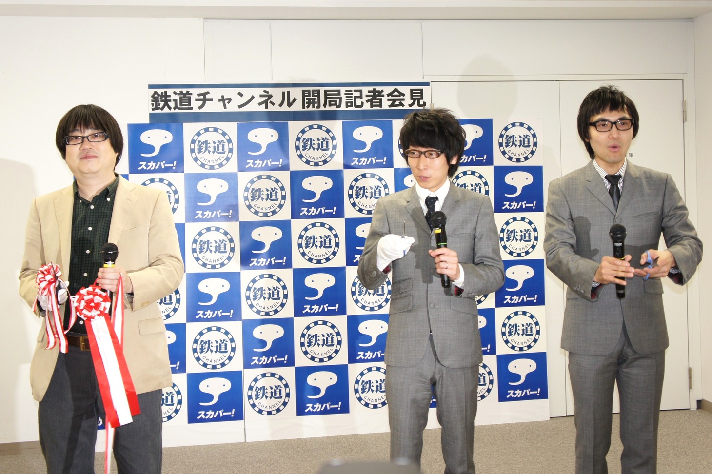テープカットには六角精児（左）が登場。「鉄道チャンネル、出発進行！」という久野アナの掛け声とともにテープカットは執り行なわれ、吉川は「1964年の東海道新幹線開通を思い出す」と感慨ひとしおの様子だった。