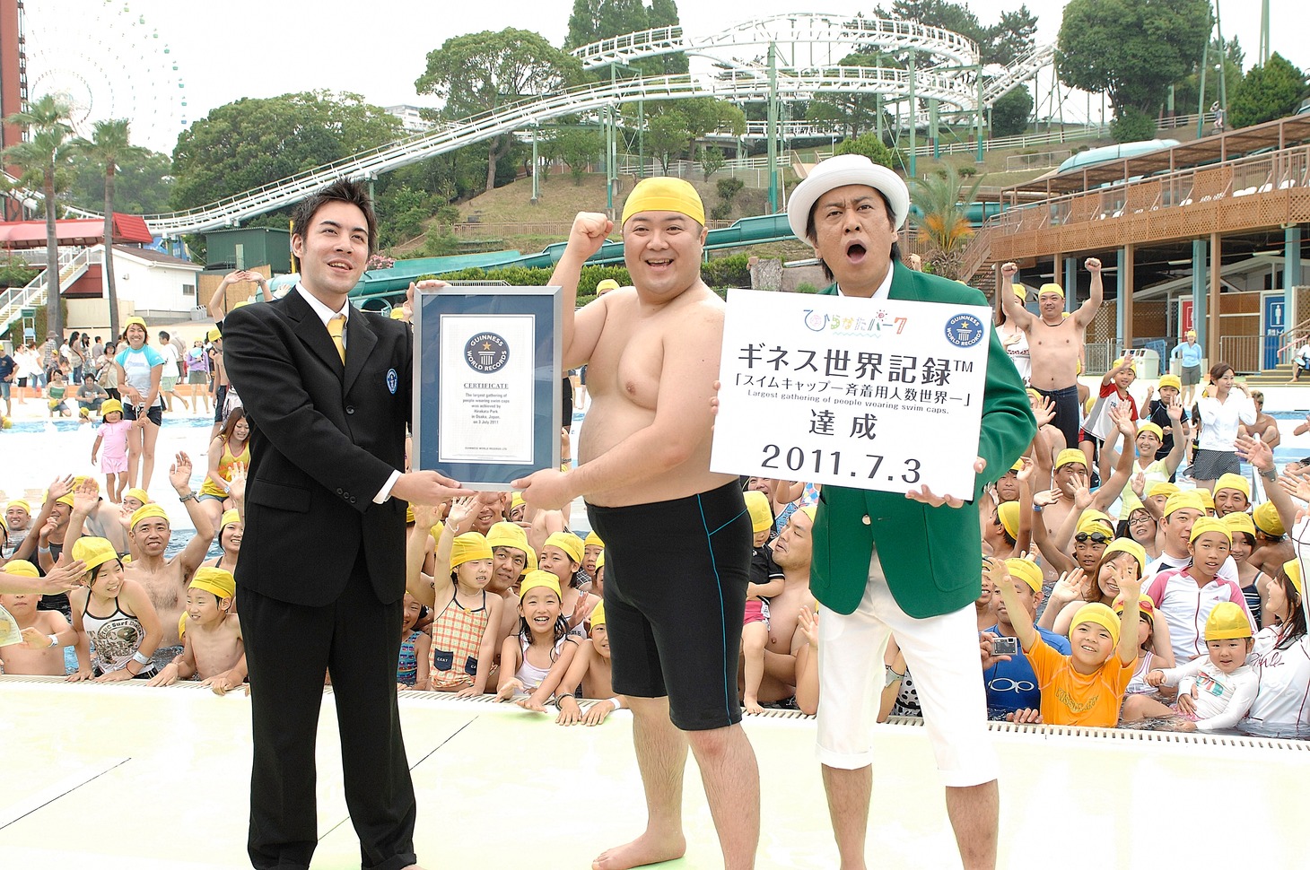 大阪・ひらかたパークにて見事「スイムキャップ一斉着用人数世界一」のギネス世界記録を達成したひらパー兄さんことブラックマヨネーズ小杉（中央）と、計測員を務めた相方・吉田（右）。