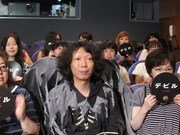 観客席に座り撮影準備を待つ家城。