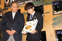 300年前に刊行された魚類図鑑を手にするピース綾部（中央）。