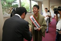 会見後三若はさっそく報道陣に「秋田お笑い大使」の名刺を配布。(c)吉本興業