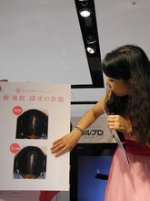 頭皮の状態をパネルを使って説明する椿鬼奴。