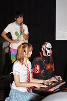 佐藤かよと鉄拳（手前左から）の対戦風景。佐久間一行（奥）も見守る。