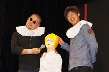 イベントの進行役としてステージに終始たたずんでいたビニール製の人形（中央）と、野性爆弾。