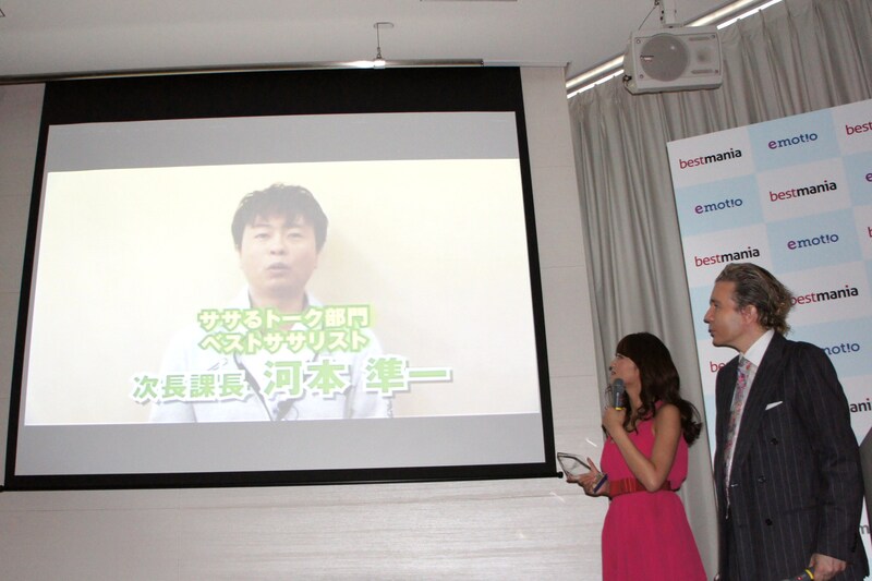 「株式会社エモーチオ 新規事業発表会 ベストササリスト授賞式」にビデオメッセージを寄せた次長課長・河本と、その映像を見守る原幹恵、デーブ・スペクター（左から）。