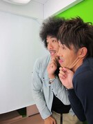 プリクラの撮影機から指示されたポーズをとる2人。