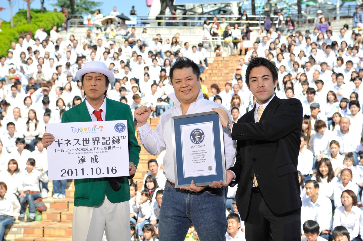 ひらかたパークを舞台にした「一斉にシャツの襟を立てた人数世界一」への挑戦で、見事ギネス記録を達成したブラックマヨネーズと、2人に認定証を渡すギネス公式認定員のショーン・カニーン氏（左から）。
