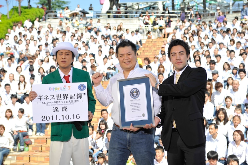 ひらかたパークを舞台にした「一斉にシャツの襟を立てた人数世界一」への挑戦で、見事ギネス記録を達成したブラックマヨネーズと、2人に認定証を渡すギネス公式認定員のショーン・カニーン氏（左から）。