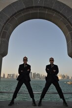 カタール滞在1日目。イスラム博物館の庭園にて、ドーハ、ウェストベイ地区の高層ビルを背に記念撮影を行うが～まるちょば。