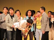 受賞は日刊スポーツより。舞台上で行われた記念撮影では新宿カウボーイ・かねきよが写り込もうと必死に。