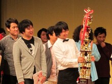 記念のトロフィーと副賞の目録を手にしたトップリード。