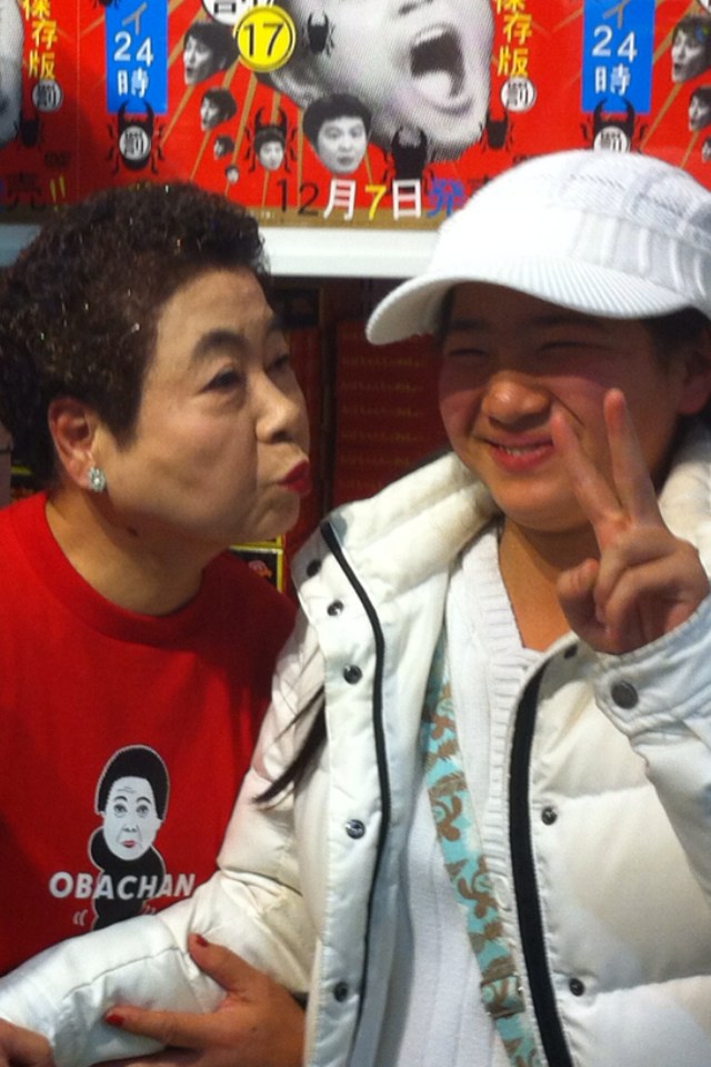 おばちゃん（左）との記念撮影に挑むファン。