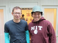 明日1月17日から31日 まで、COWCOWよしのギャラリーHIBOU HIBOUにて写真展 「キュートン in Paris」を行う河村正和カメラマン（左）。2人の奥にはキュートンとエッフェル塔の写真が。