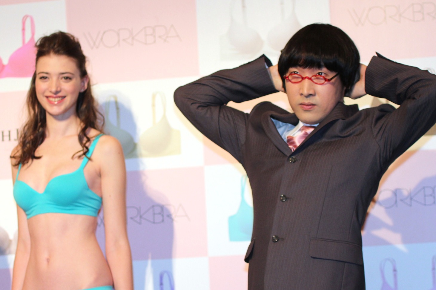 モデルと同様のセクシーポーズを取りながら「どこに需要が？」「カメラを撮ってもデジタルだからすぐ消せる」「足がつりそう」などと話した山里（右）。