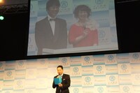 会見で司会を務めた東京会場の東野幸治（前方）と、スクリーンに映る大阪会場の藤井隆、未知やすえ（左から）。