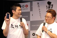 「でっかくなっちゃった！」の耳が実はiPhoneケースだったことを明かすマギー審司（左）。