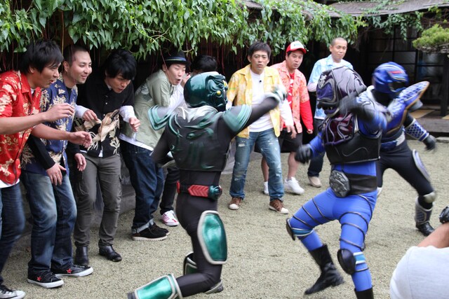 「フットンダ in 沖縄 極上グルメモジりツアー」後編で沖縄のご当地ヒーロー・琉神マブヤーのアクションを見守る芸人たち。(c)中京テレビ