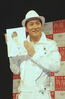 アメリカザリガニ平井が描いたイラストを手にフォトセッションに応じる小島。