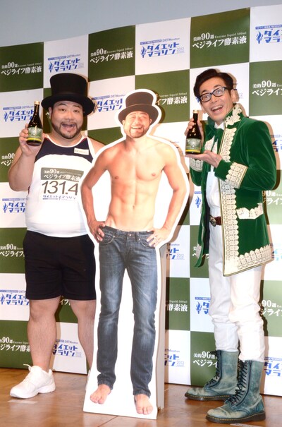 「ベジライフ酵素液Presents ダイエットマラソン2012 SUMMER」でダイエットに挑戦する髭男爵・山田ルイ53世（左）と、特別サポーターのひぐち君（右）。真ん中のパネルは山田が目標の12kg減量を達成した場合を想定して作られたもの。