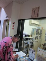 名古屋市野鳥観察館に貼ってもらうサインを書くRG。頭上にはぐっさんのサイン。